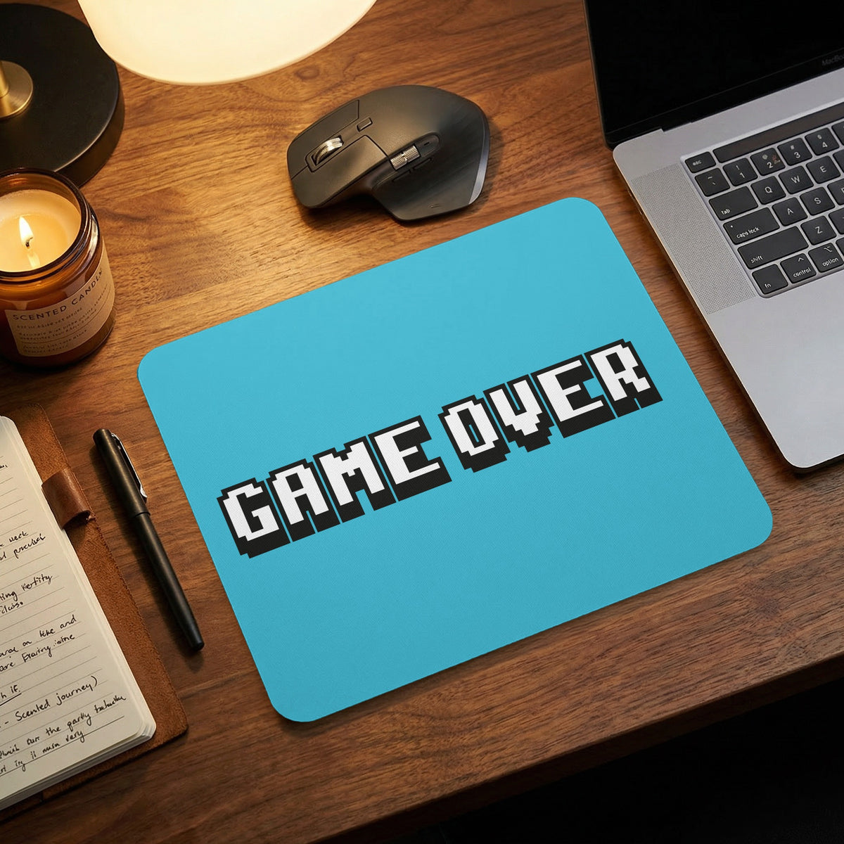 Light blue mouse pad with pixelated black and white text reading GAME OVER on a wooden desk.