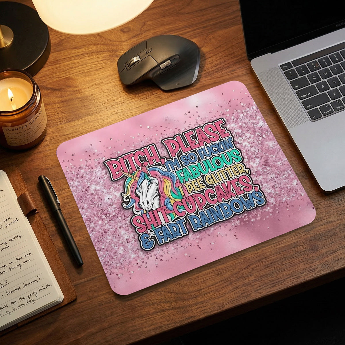 Pink mousepad featuring a colorful unicorn and sarcastic text, placed on a wooden desk with a laptop and mouse.