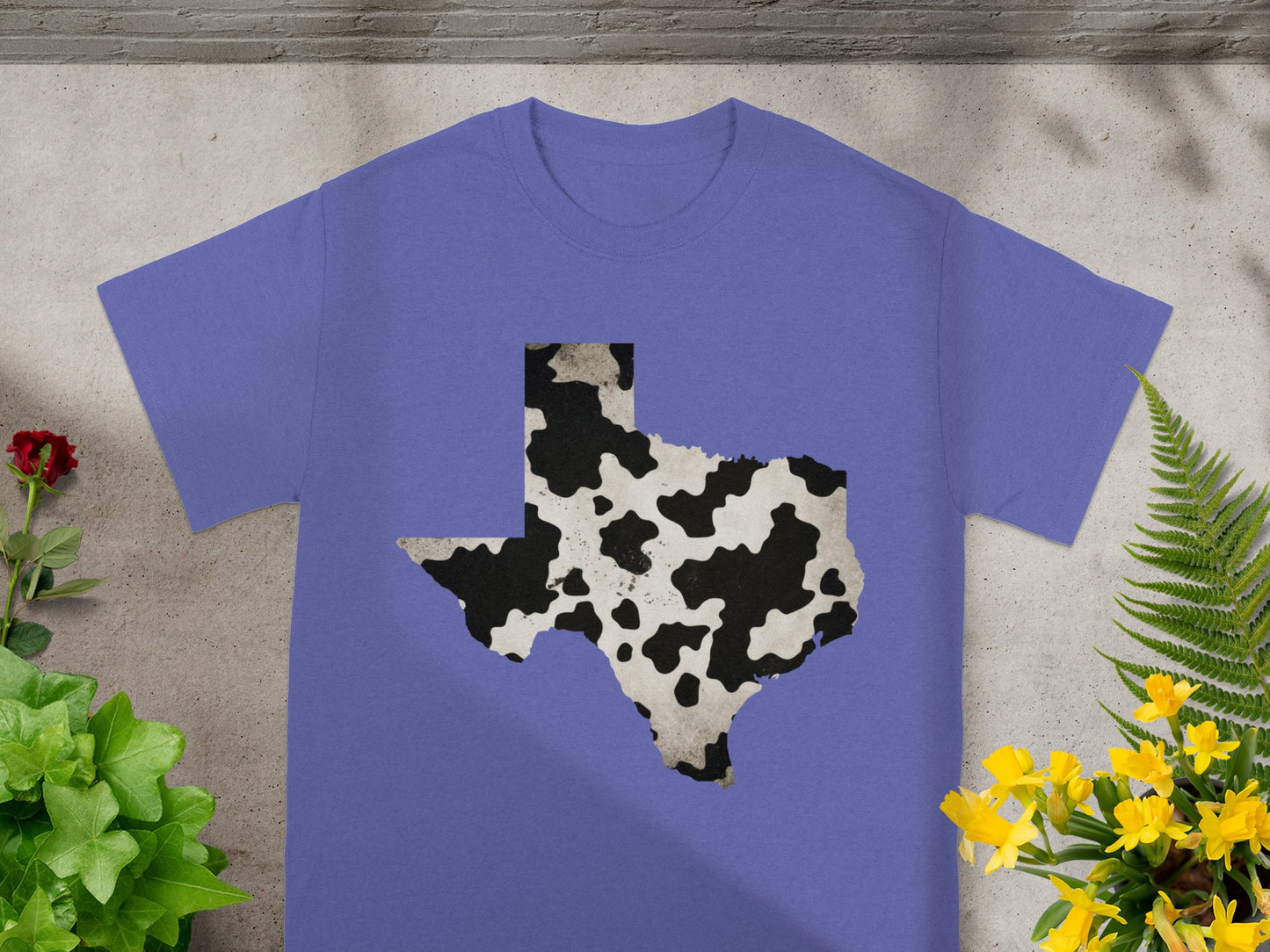 Purple t-shirt with a black and white cow print Texas outline design.