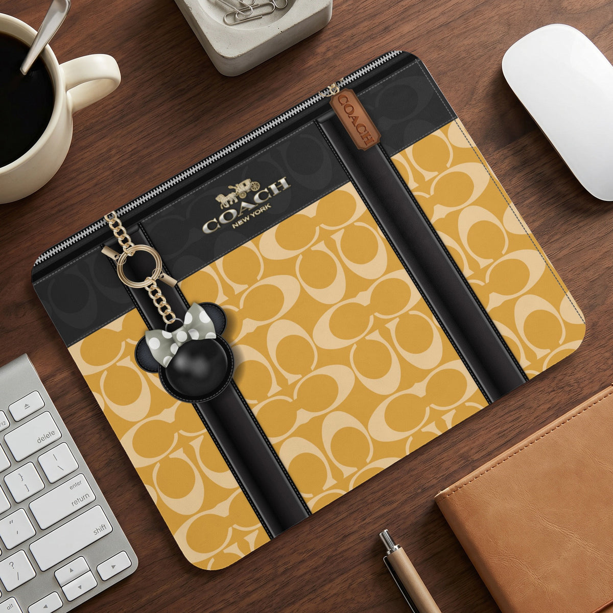 Coach clutch with signature pattern, Disney character charm, and gold hardware.
