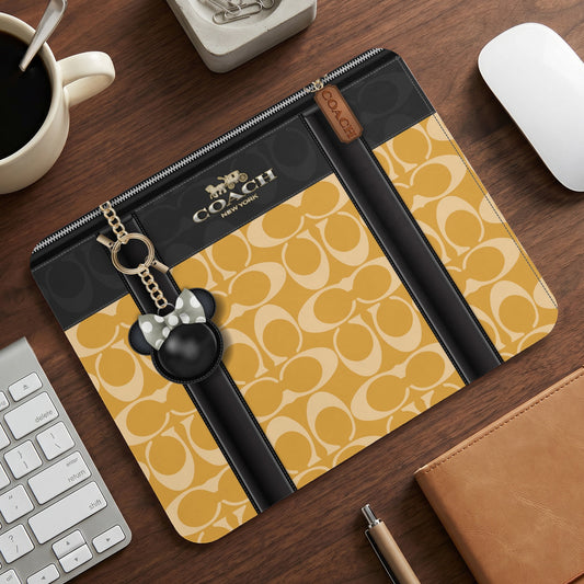 Coach clutch with signature pattern, Disney character charm, and gold hardware.