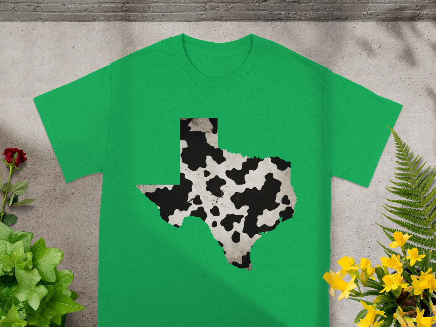 Green t-shirt with a cow print Texas outline graphic design.