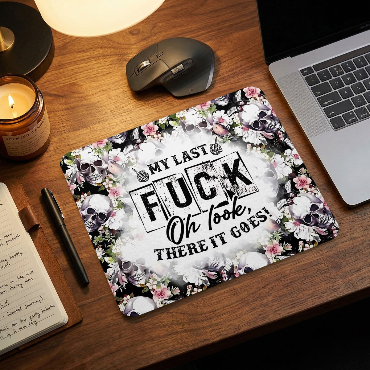 Rectangular mousepad with skulls, pink flowers, and the text My Last Fuck Oh Look There It Goes on a wooden desk.