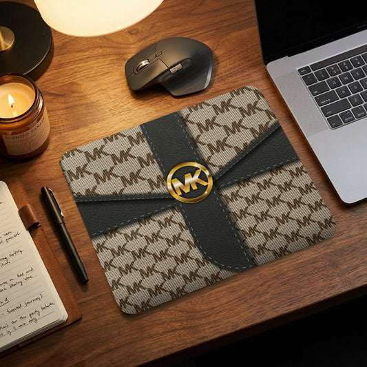 Mousepad with Michael Kors logo pattern and grey accents on wooden desk.