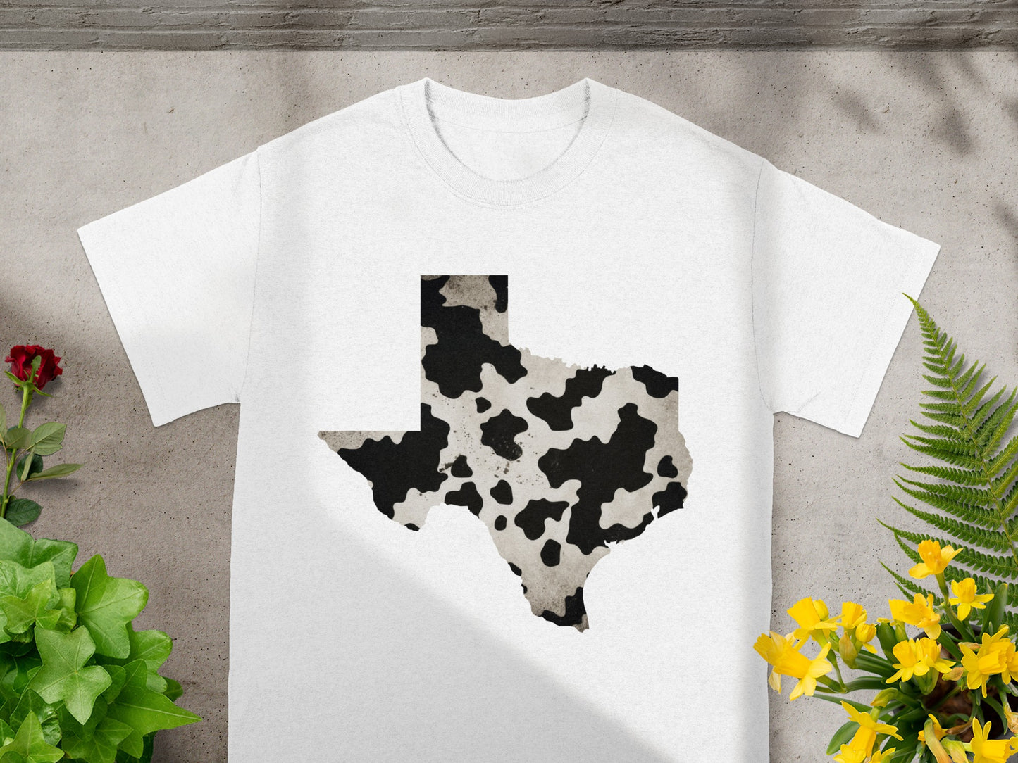 White t-shirt with a cow print Texas outline graphic.
