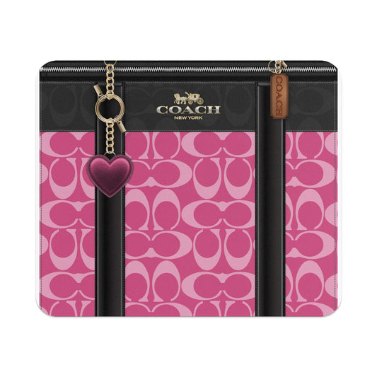 Coach bag with pink C monogram, black leather accents, zipper, and heart charm.